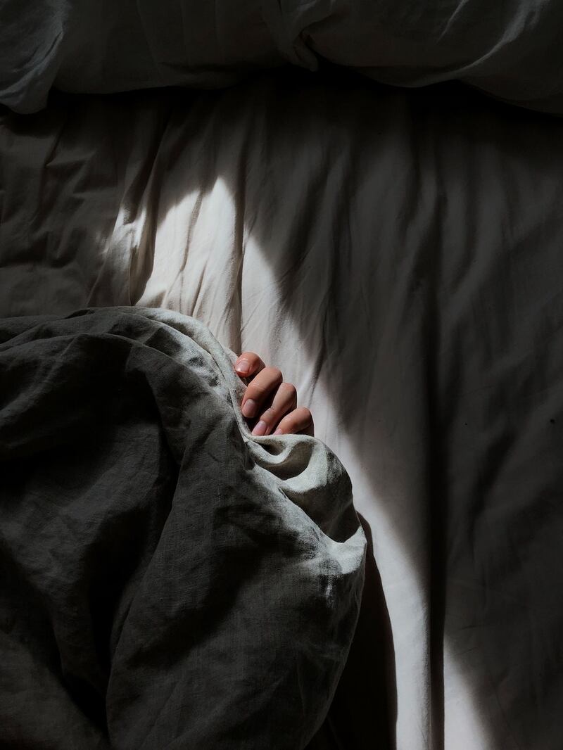 mano de mujer bajo las sabanas y sobre colchon sucio