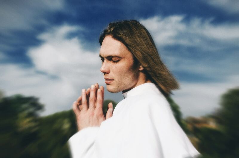 hombre vestido de blanco meditando al aire libre