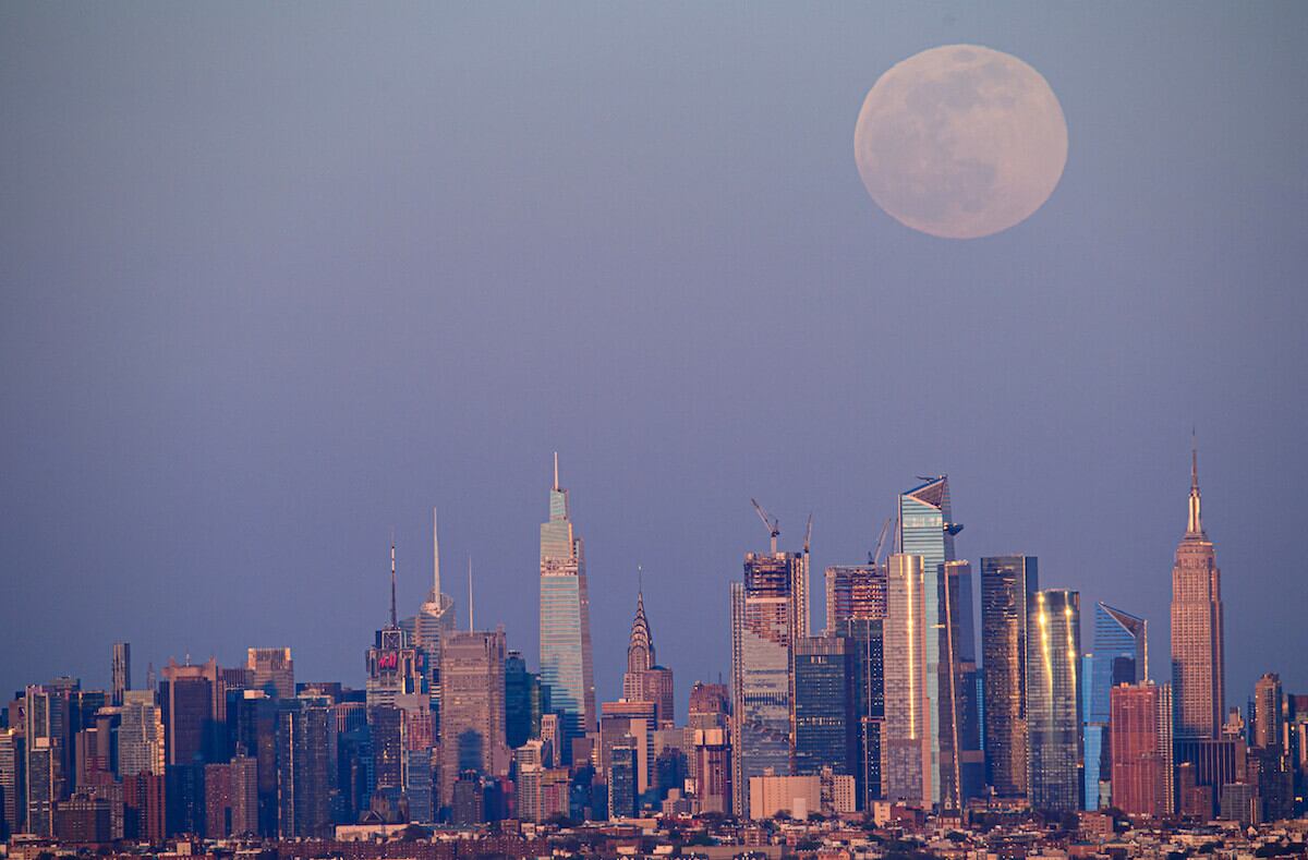 Vista de la Superluna rosa del sobre el skyline más famoso del mundo, Nueva York, en el que su enorme tamaño contrasta con los altos edificios de la ciudad. / Foto: Angela Weiss / AFP
